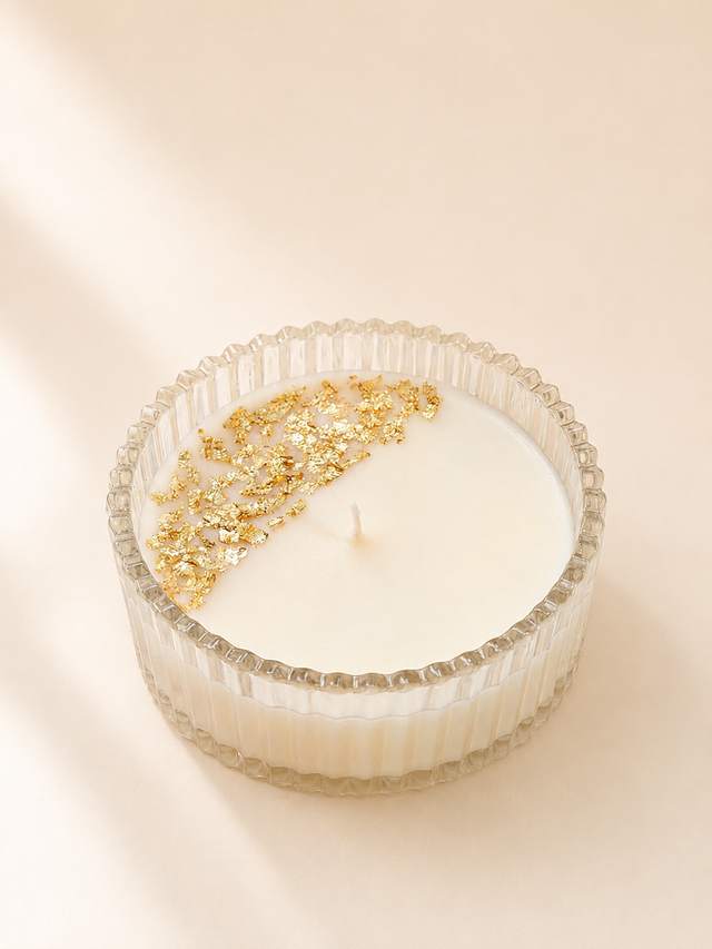 Candle with gold flakes in a ribbed glass